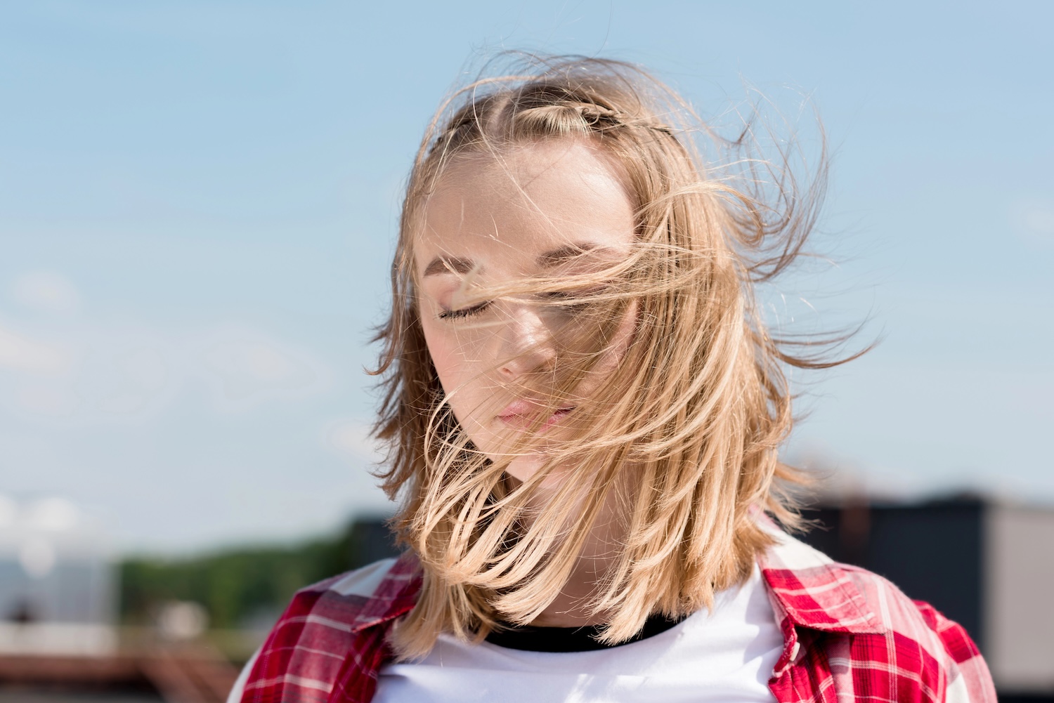 A teenage girl with hair blowing across her face