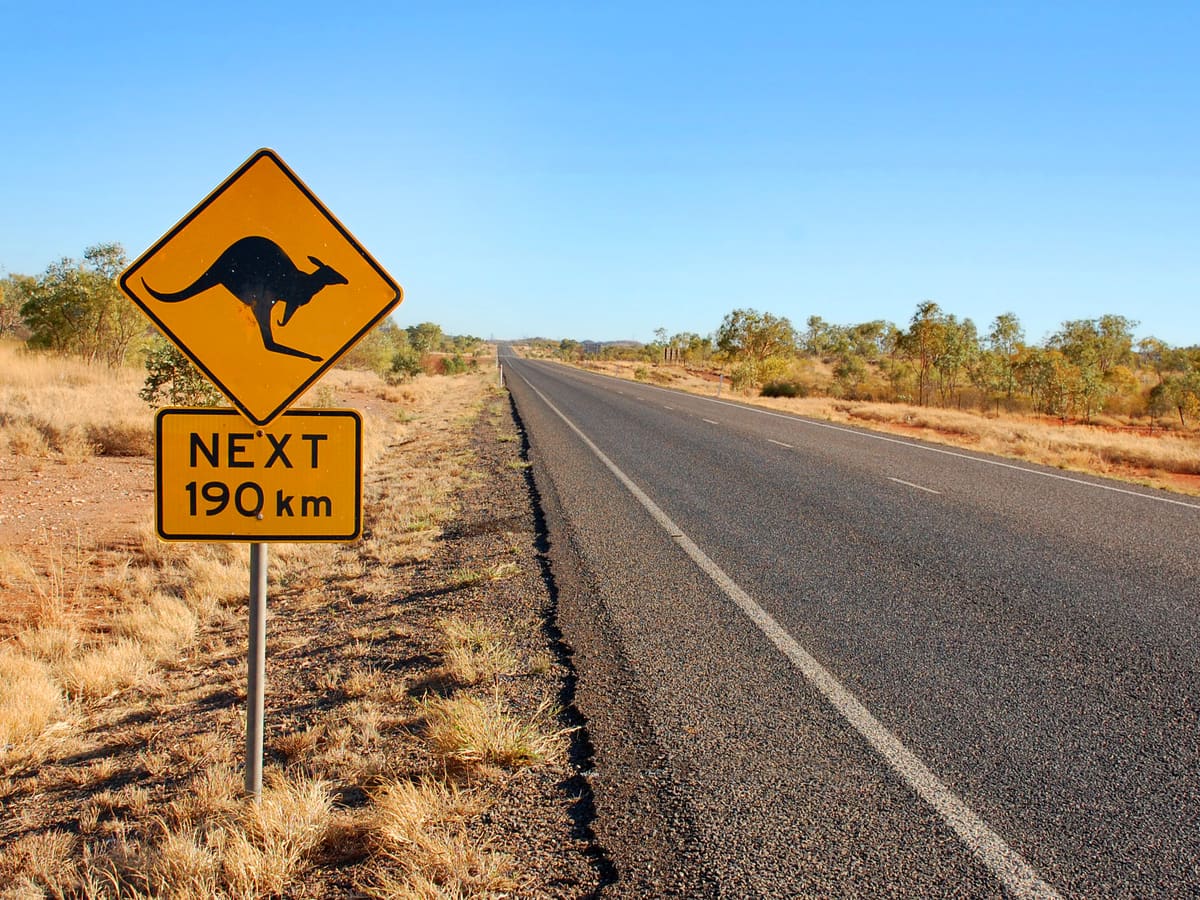 A yellow kangaroo warning sign beside an outback highway in Australia